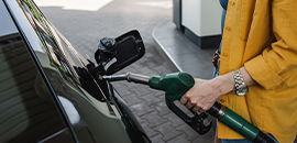 Η εικόνα απεικονίζει μια γυναίκα να γεμίζει με βενζίνη το όχημα της.