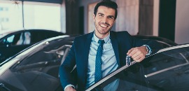 Πωλητής βγαίνει από αυτοκίνητο χαμογελώντας με τα κλειδιά στο χέρι