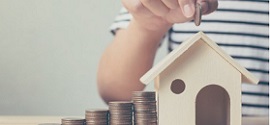Ένας κουμπαράς σπίτι που ένα παιδί βάζει ένα νόμισμα μέσα για να πετύχει έκπτωση στην ασφάλεια κατοικίας