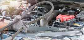 Άνθρωπος κρατά λερωμένο ιμάντα χρονισμού φορώντας προστατευτικά γάντια