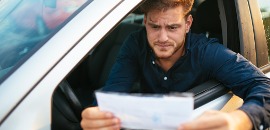 Προβληματισμένος άνδρας οδηγός διαβάζει κλήση τροχαίας που κρατά