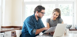 Ζευγάρι διαβάζουν έγγραφο μπροστά από τον υπολογιστή τους
