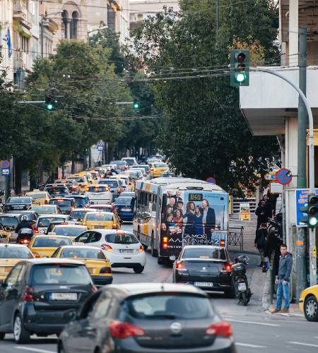 Πολυσύχναστος δρόμος της Αθήνας γεμάτος με αυτοκίνητα, ταξί και λεωφορεία.